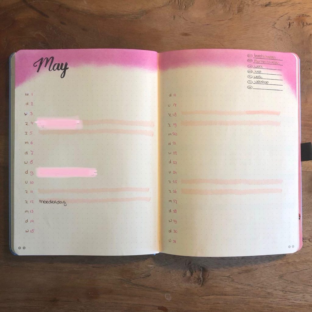 Open notitieboek met maandoverzicht mei op houten oppervlak