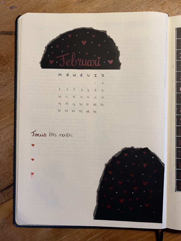 Open notitieboek met februari kalender en hartjesdecoratie op dot-grid papier