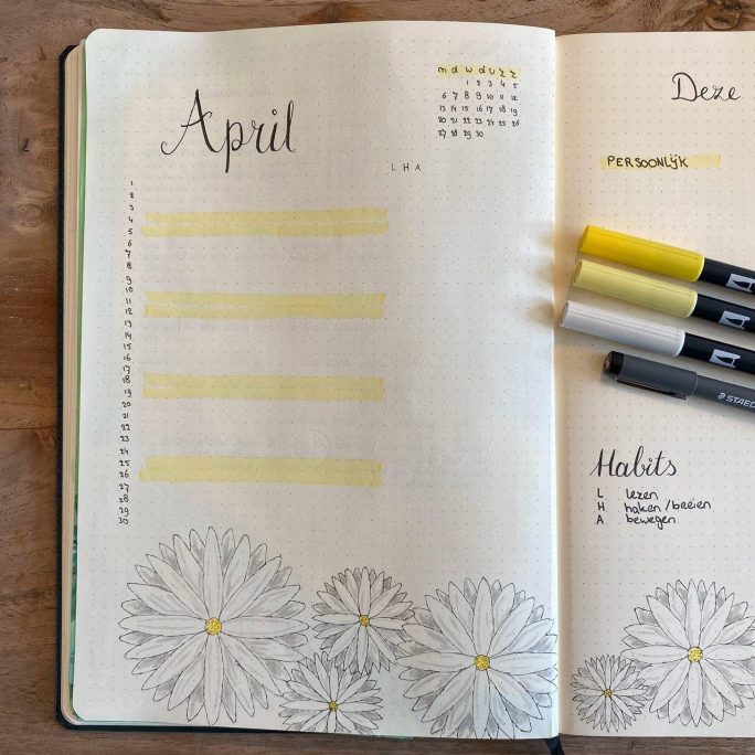 Open bullet journal met april maandoverzicht en bloemenillustraties