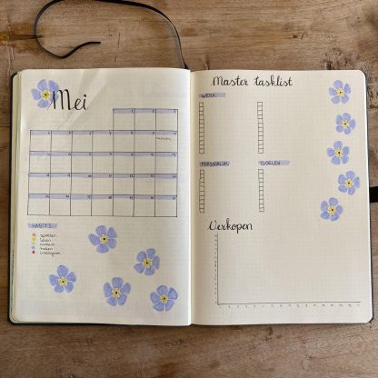 Open notitieboek met mei-planner en bloemenstickers op houten oppervlak