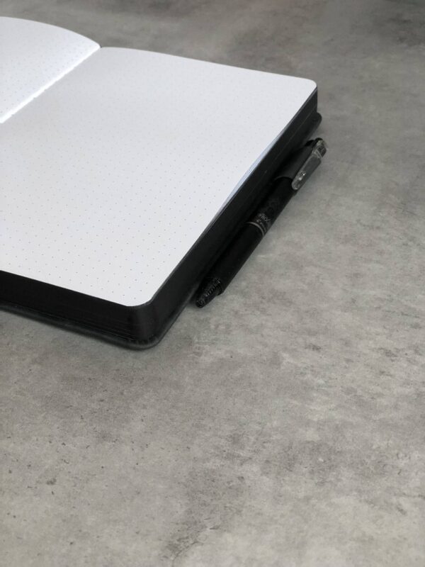 Open notitieboek met stippenpatroon en zwarte pen naast