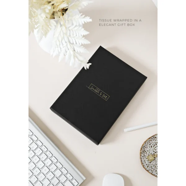 Zwarte geschenkdoos van Scribble & Dot op een bureau met witte bloemen