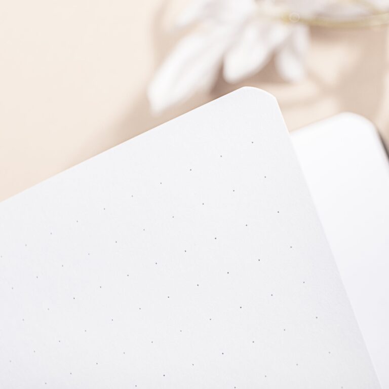 Detail van een wit notitieboekblad met dot-grid patroon