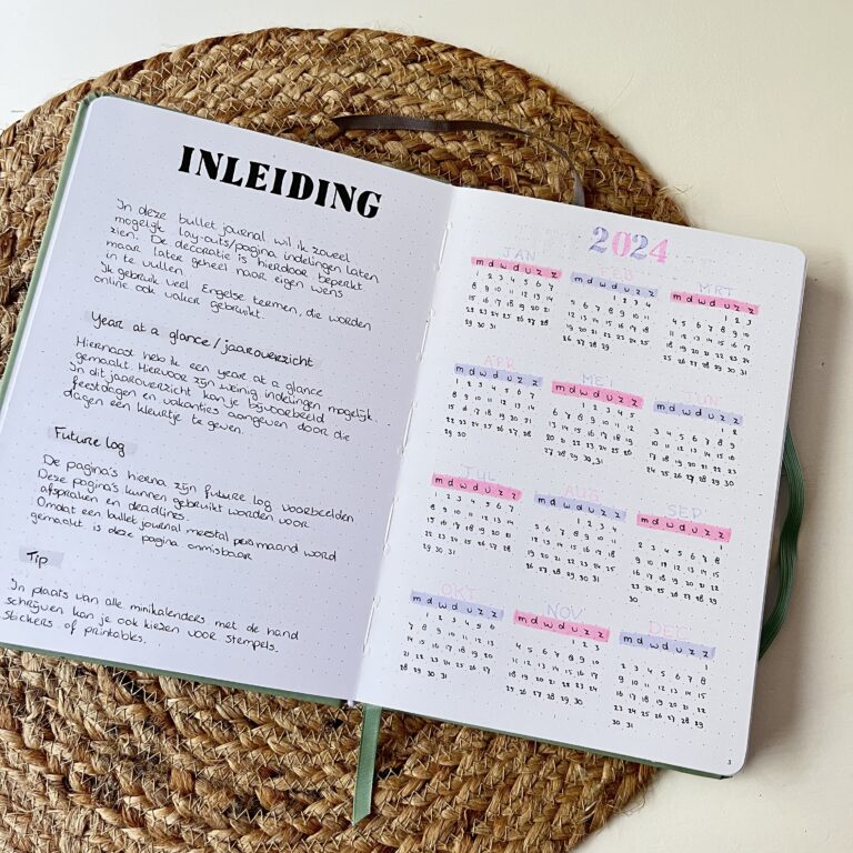 Open bullet journal met jaaroverzicht en instructies op een rieten mat