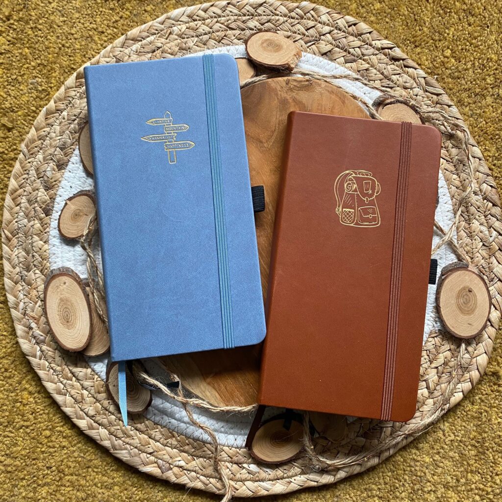 Twee reisnotitieboeken op een rieten dienblad: blauw en bruin