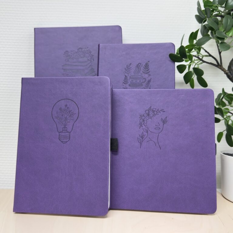 Vier paarse notitieboeken met gedrukte motieven op de kaft