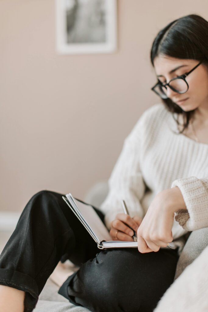 Vrouw schrijft in een notitieboek op een bank