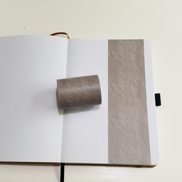 Bruine washi tape op een open notitieboek met puntjes