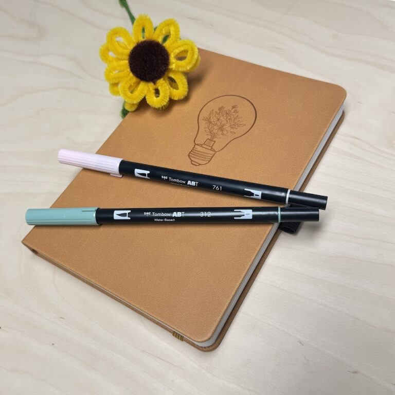 Bruin notitieboek met lichtgevende lamp-afbeelding en twee Tombow ABT-pennen