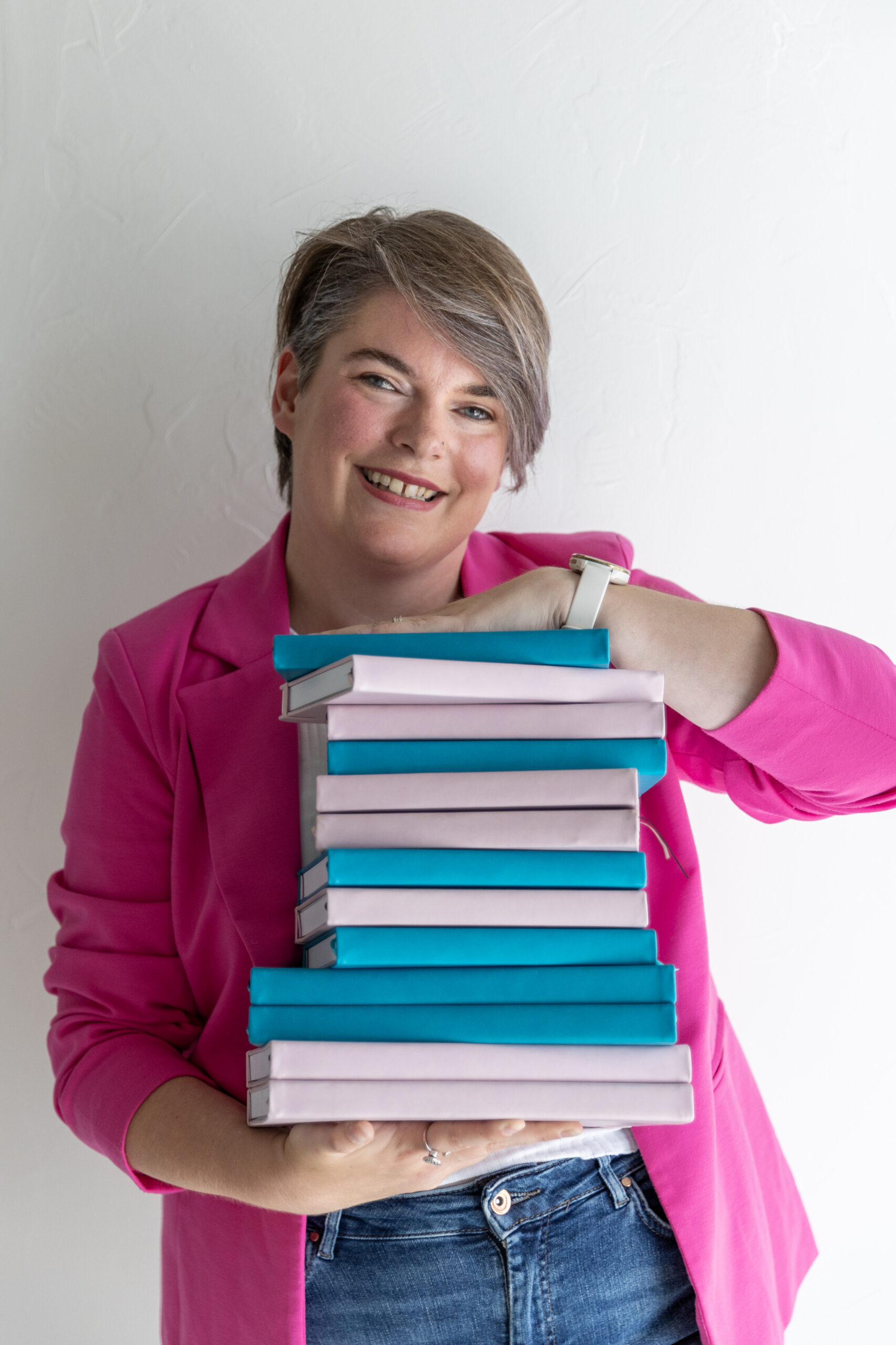 Vrouw houdt stapel notitieboeken vast tegen witte achtergrond