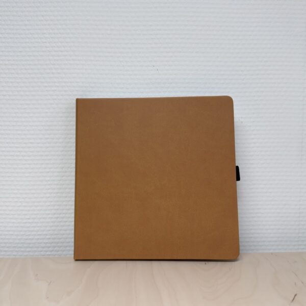 Bruine softcover notitieboek op houten oppervlak tegen witte muur