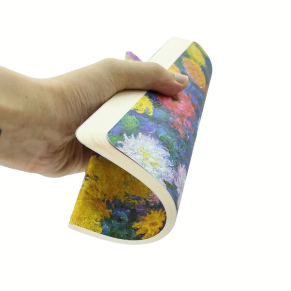 Hand houdt een notitieboek vast met een kleurrijk bloemmotief op de kaft