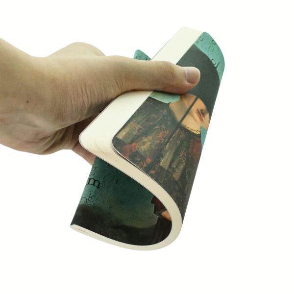 Hand houdt een gebogen notitieboek vast met een groene cover en letterpatroon